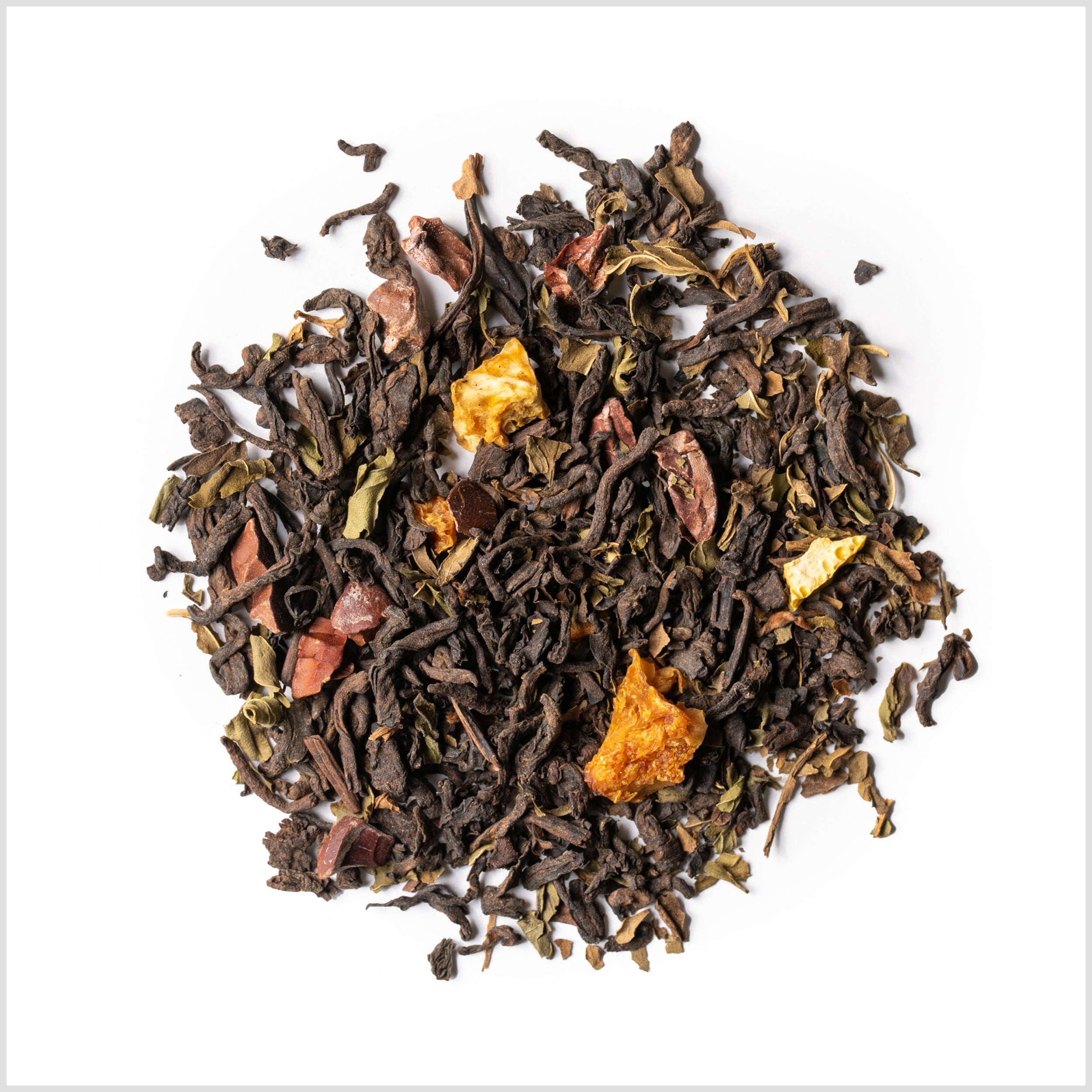 Pile of loose Chocolate Peppermint Pu-erh to show full leaf pu-erh tea, dried orange peel, cacao and peppermint.
