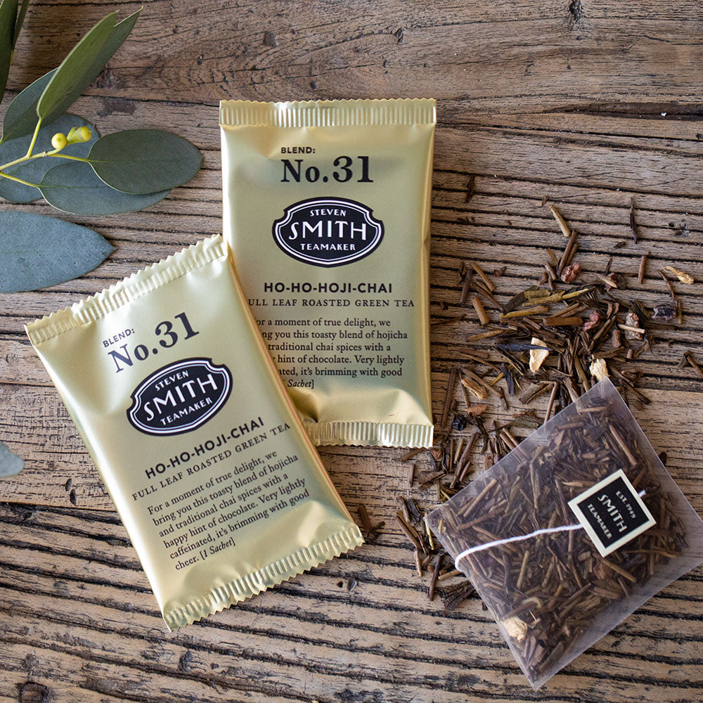 Two gold metallic sachets of tea on wooden background.
